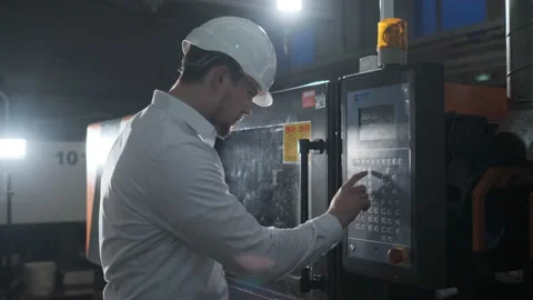 Engineer in a white helmet and white clothes working on the machine at the Stock Footage 107413021