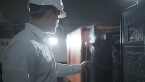Engineer in a white helmet and white clothes working on the machine at the Stock Footage 107413508