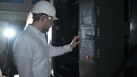 Engineer in white helmet and white clothes includes the machine in the factory Stock Footage 107415415