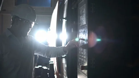 Engineer in white helmet and white clothes includes the machine in the factory Stock Footage 107415577