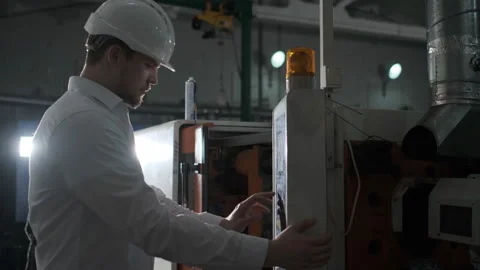 Engineer in a white helmet and white clothes working on the machine at the Stock Footage 114504349