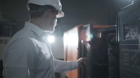 Engineer in a white helmet and white clothes working on the machine at the Stock Footage 114504857
