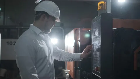 Engineer in a white helmet checks the condition of the Metalworking machine Stock Footage 107412881