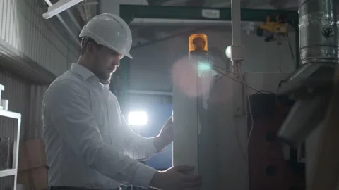 Engineer in a white helmet checks the condition of the Metalworking machine Stock Footage 114503995