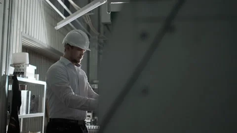 Engineer in a white helmet checks the condition of the Metalworking machine Stock Footage 114504072