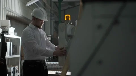 Engineer in a white helmet checks the condition of the Metalworking machine Stock Footage 114504147
