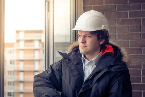 Engineer in a white helmet looking out the window. Soft focus, toned. Stock Photos