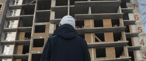 Engineer in white helmet observes construction site with unfinished brick house Stock Footage 119496933