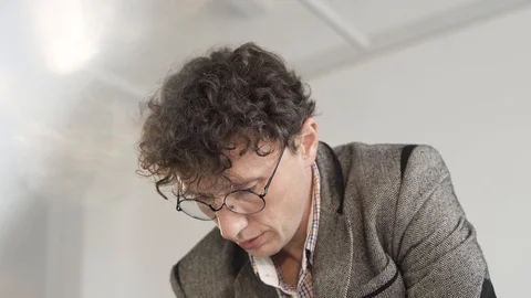 Engineer in a white room with an eraser erases a drawing or sketch on paper Stock Footage 124941818