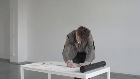Engineer in a white room with an eraser erases a drawing or sketch on paper Stock Footage 124941886