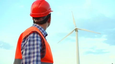 Engineer at wind farm power plant is looking on wind turbine Stock Footage 137428148