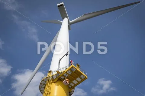 Engineer On Wind Turbine At Offshore Windfarm, Low Angle View