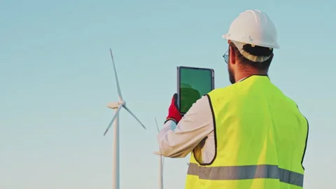 Engineer in Wind Turbine park checks turbines using a tablet with chroma key Stock Footage 246380232