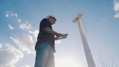 Engineer at windmill power plant with tablet in hand on sky background Video stock 89668690