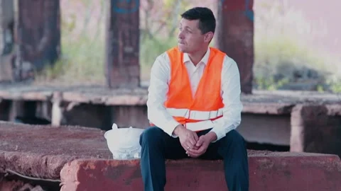 An engineer without work sits at a construction site. Personnel crisis. Stock Footage 138172287