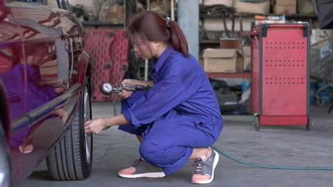 Engineer woman checking pressure and inflating car tire in garage. Stock Footage 173650341