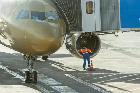 Engineer worker checks engine fan of airplane before departure. Foto stock