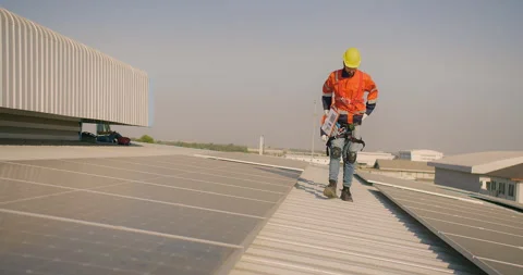 Engineer worker in a high-visibility vest walks along a solar panel array on a b Stock Footage 279298581