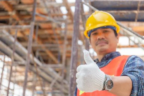 Engineer / worker man hand giving thumb up over blurred construction site Photos