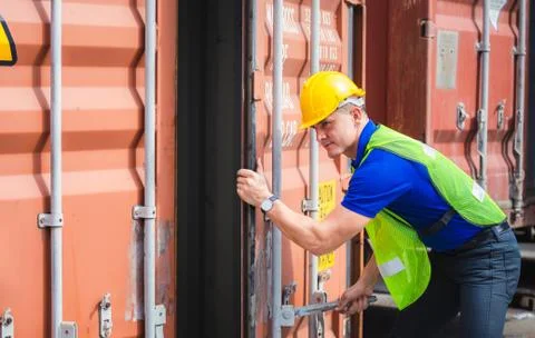 Engineer worker man in hardhat and safety vest checking containers box from c Фото
