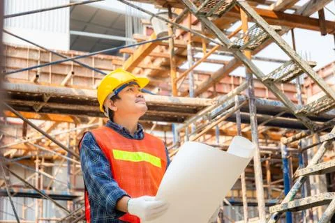 Engineer / worker man holding blueprint checking and planning project at site Stockfoto's