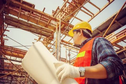 Engineer / worker man holding blueprint checking and planning project at site Фото