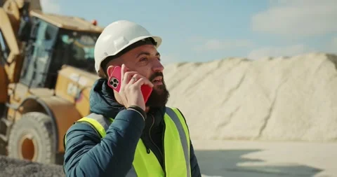 Engineer worker with a phone on the background of an excavator at a cement plant Stock Footage 277595766