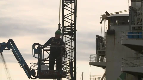 Engineer worker standing on crow's nest arm inspecting ship at dusk Stock Footage 116512005