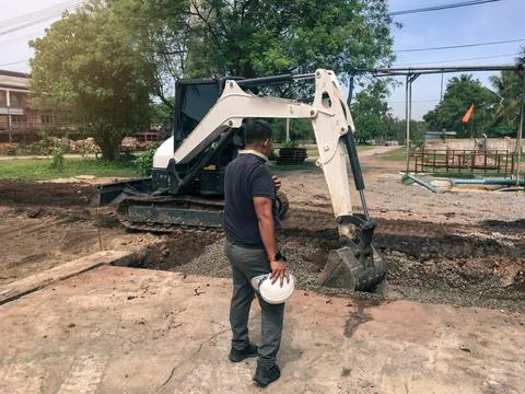 Engineer worker steering a backhoe to renovate the site Stock Photos