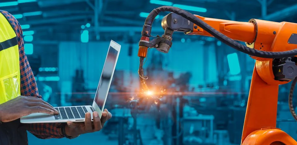 Engineer worker using laptop computer program control Robotic Arm Welding wit Stock Photos
