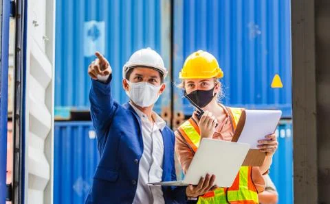 Engineer worker wearing protection face mask checking containers box from cargo Stockfoto's