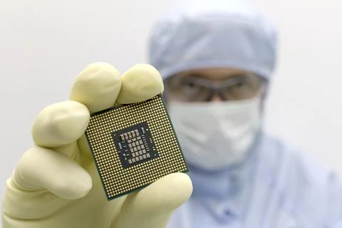 An engineer working in a clear room wearing a special uniform and protective Stock Photos