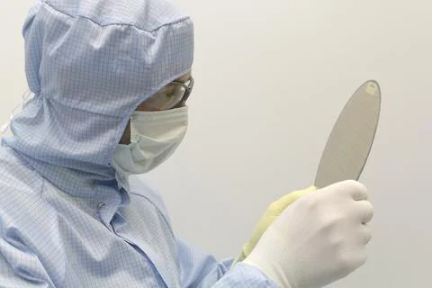 An engineer working in a clear room wearing a special uniform and protective Stock Photos