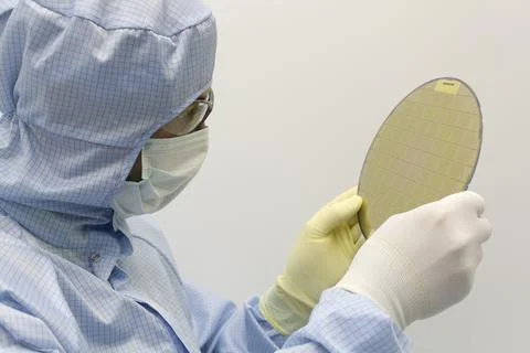 An engineer working in a clear room wearing a special uniform and protective Stock Photos