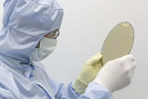 An engineer working in a clear room wearing a special uniform and protective Stock Photos