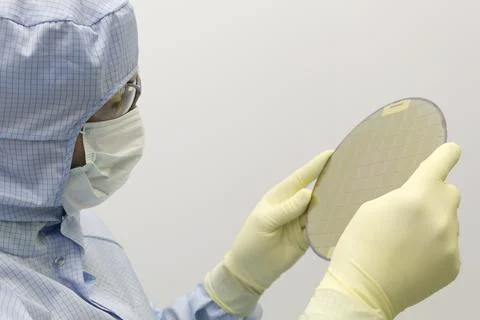 An engineer working in a clear room wearing a special uniform and protective Stock Photos