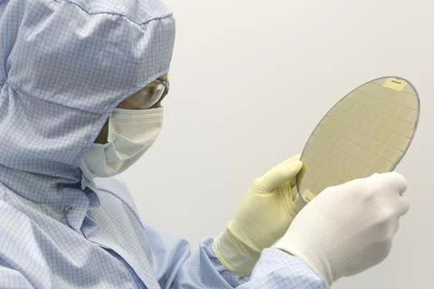 An engineer working in a clear room wearing a special uniform and protective Stock Photos