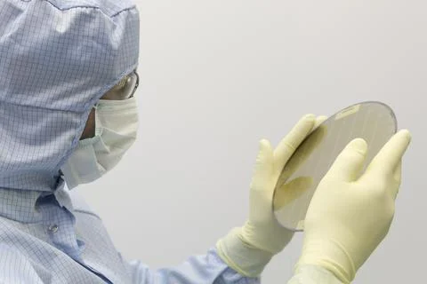 An engineer working in a clear room wearing a special uniform and protective Stock Photos
