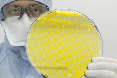 An engineer working in a clear room wearing a special uniform and protective Stock Photos