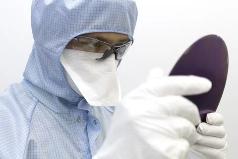 An engineer working in a clear room wearing a special uniform and protective Stock Photos