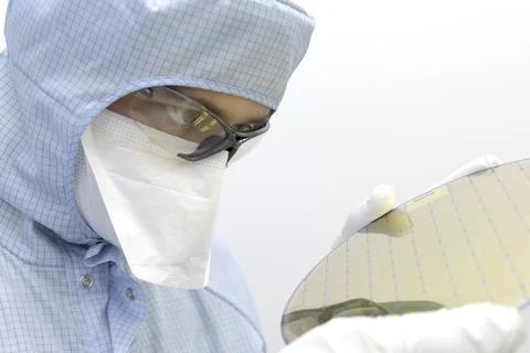 An engineer working in a clear room wearing a special uniform and protective Stock Photos