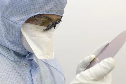 An engineer working in a clear room wearing a special uniform and protective Stock Photos