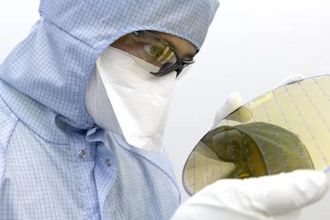 An engineer working in a clear room wearing a special uniform and protective Stock Photos