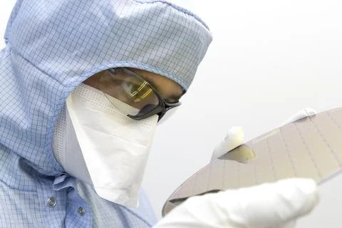 An engineer working in a clear room wearing a special uniform and protective Stock Photos