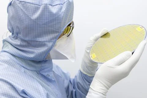 An engineer working in a clear room wearing a special uniform and protective Stock Photos