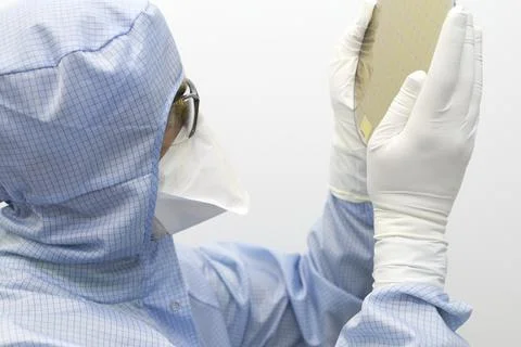 An engineer working in a clear room wearing a special uniform and protective Stock Photos