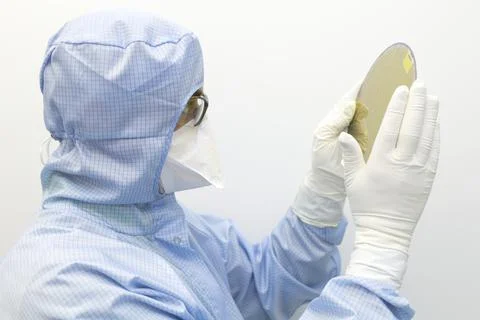 An engineer working in a clear room wearing a special uniform and protective Stock Photos