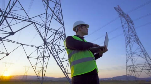 Engineer working in front of power lines at sunset. Stock Footage 203851389