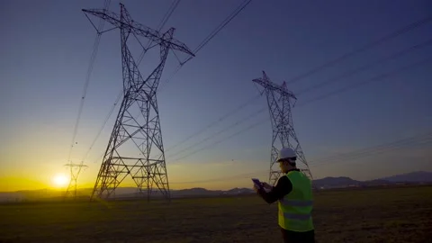 Engineer working in front of power lines at sunset. Stock Footage 203852991