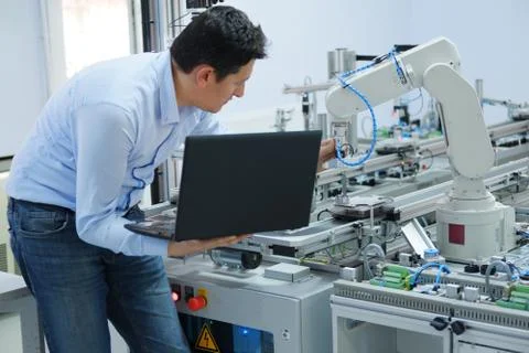 Engineer is working on laptop to programming smart factory automation Stock Photos